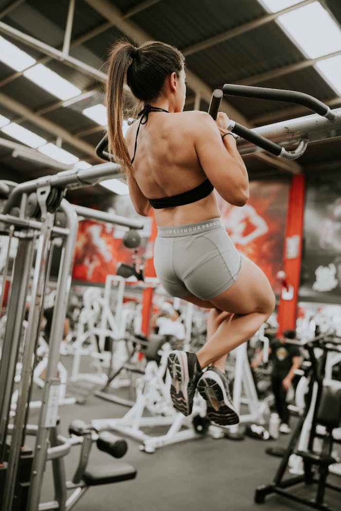 Strong woman doing pull-ups at a gym showcasing fitness and strength.